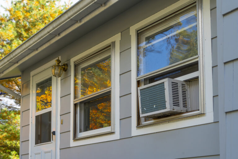 air conditioner installed on house window reflecting autumn leaf color
