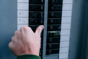 Close-Up Shot of a Caucasian Man's Hand Checking or Turning on/off a Circuit Breaker on a home outdoor panel in the USA