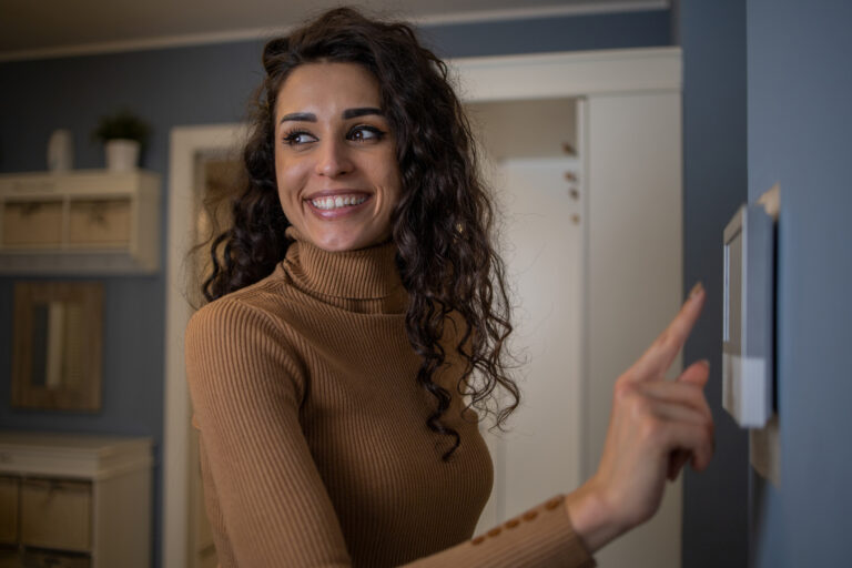 Woman using a smart thermostat system in her home