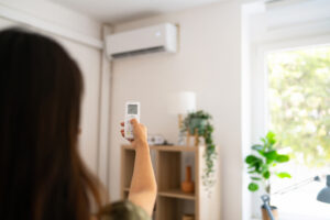 Woman turning on air conditioner with remote control.
