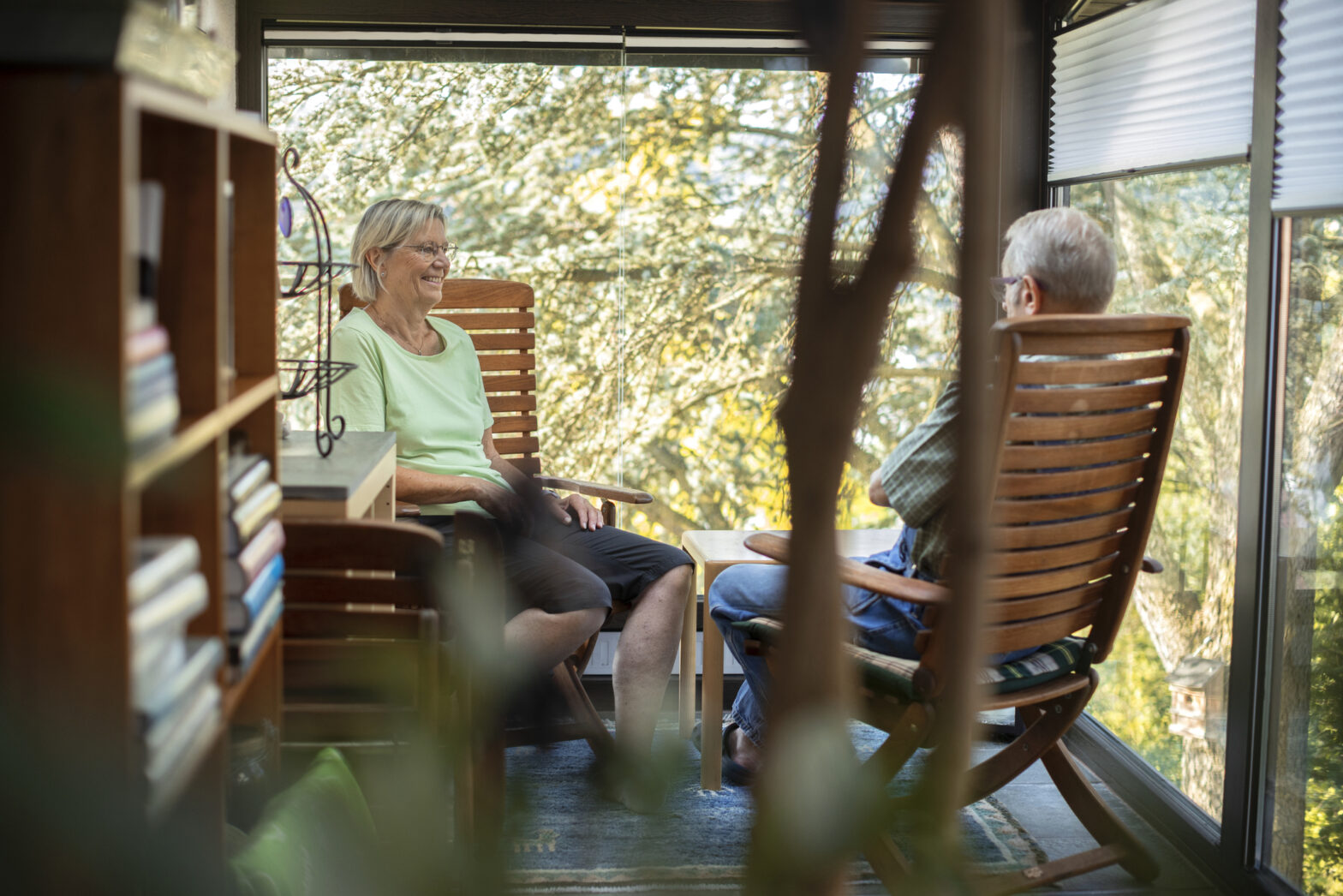 Senior couple sitting on wooden chairs in sun room